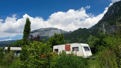 Wohnwagen zwischen Sträuchern, dahinter die Felswand des Flimsersteins