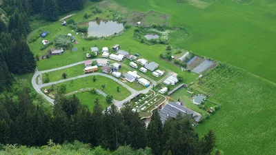 Der Campingplatz aus der Luft: Stellplätze, Weiher und das Erdhaus zwischen Wald und Feldern
